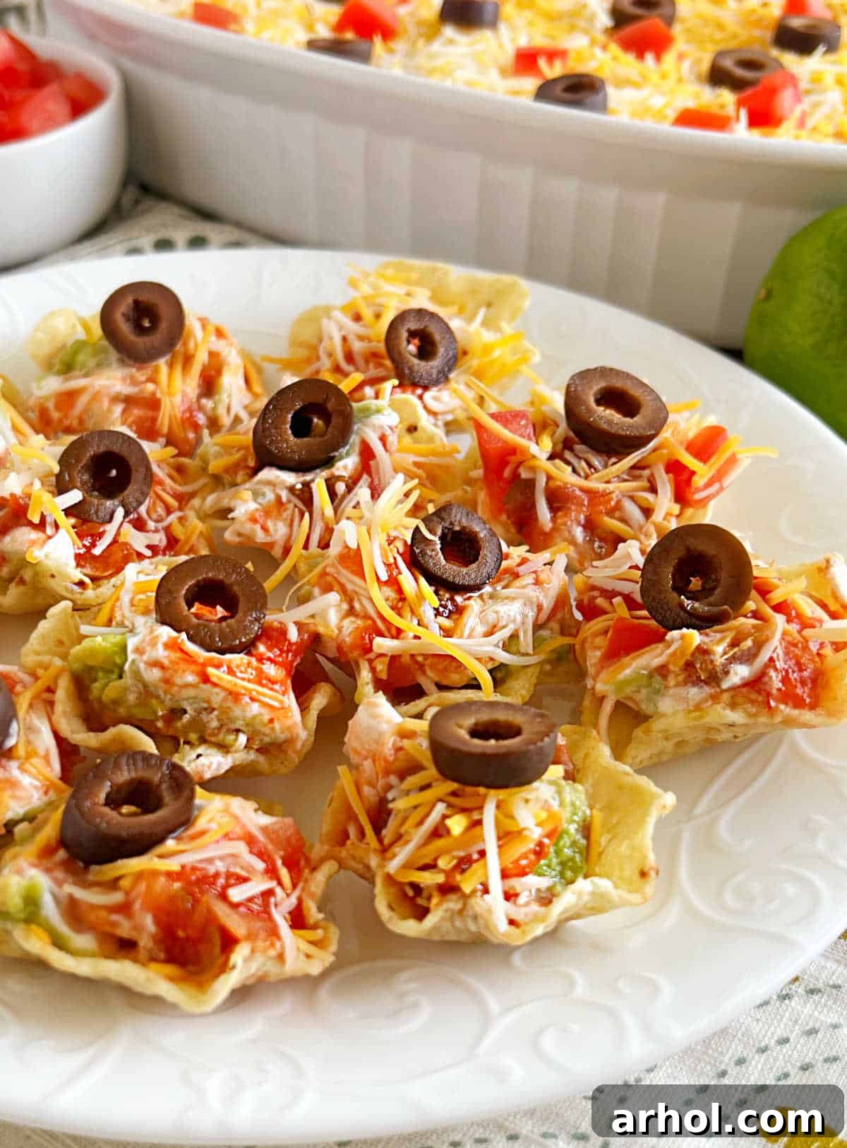Individual seven-layer dip bites served in convenient tortilla chip Tostitos scoops, arranged beautifully on a platter.