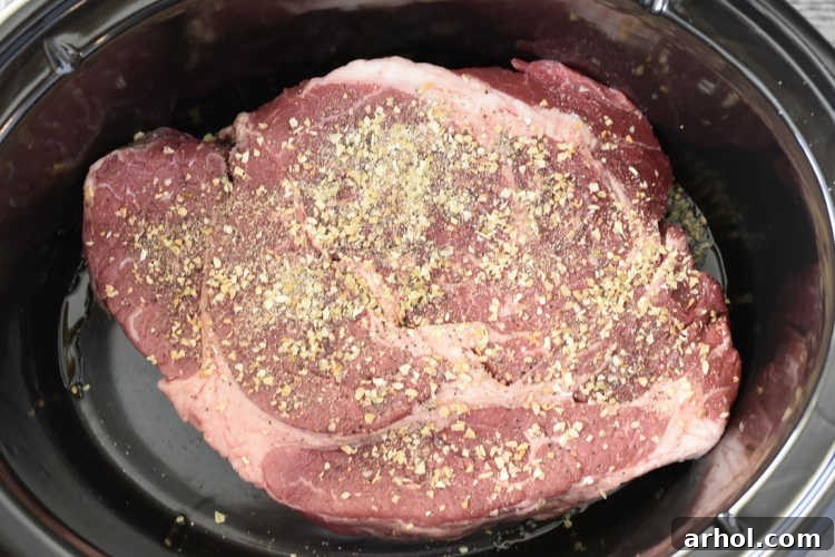 Beef chuck roast seasoned with sea salt, garlic powder, pepper, and minced onions in a slow cooker