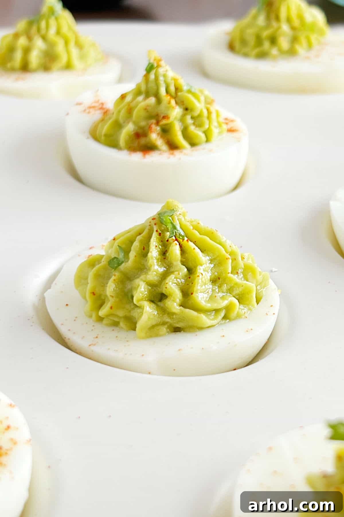 Delicious Guacamole Deviled Eggs Ready to Serve tray of guacamole deviled eggs with paprika.