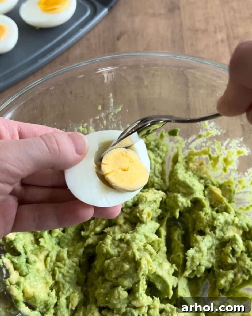 Mashing Egg Yolks with Avocado spoon egg yolk into mashed avocados.