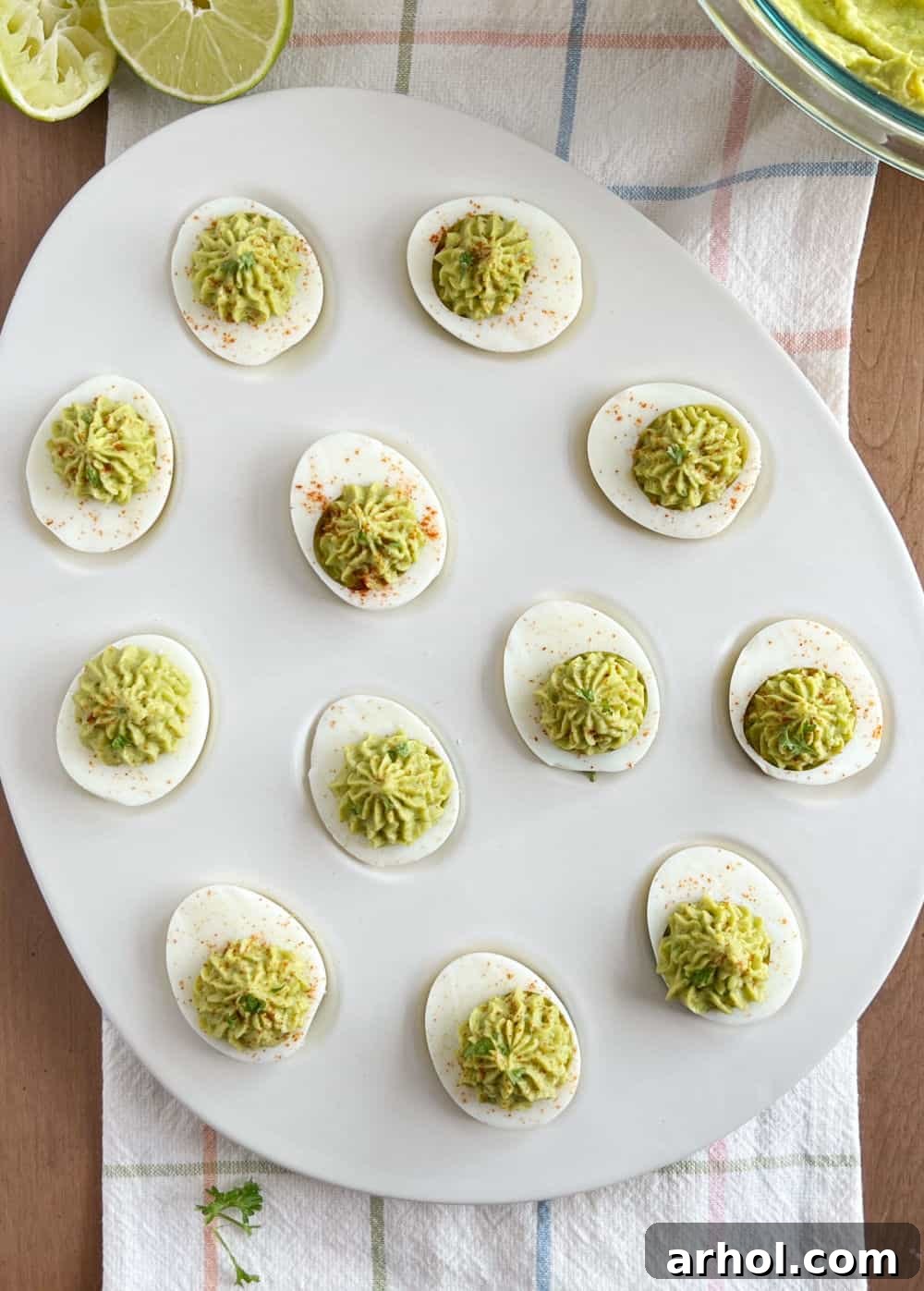 Avocado Deviled Eggs with Fresh Garnish avocado deviled eggs with cilantro and paprika in a serving platter.