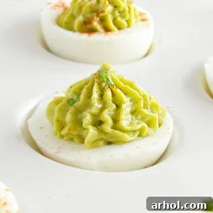 guacamole deviled eggs with piped avocado filling.