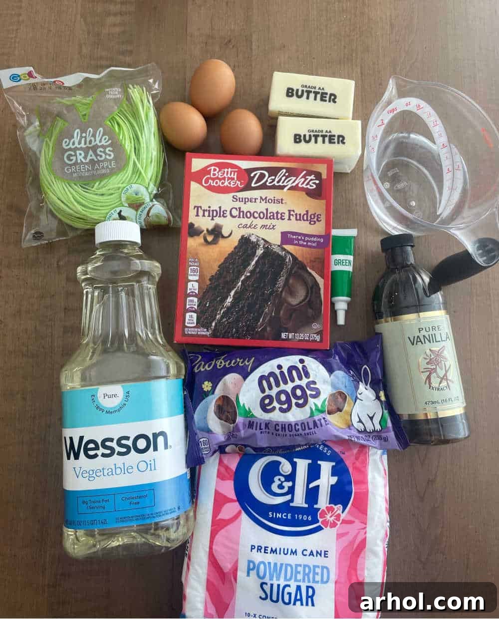 Essential ingredients laid out for making Bird's Nest Cupcakes: a box of cake mix, fresh eggs, cooking oil, and canned frosting.