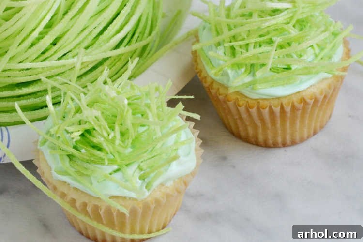Close-up of frosted cupcakes adorned with meticulously arranged edible Easter grass, forming individual bird's nests.