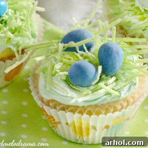 Easter cupcakes topped with edible grass and chocolate candy eggs in a nest