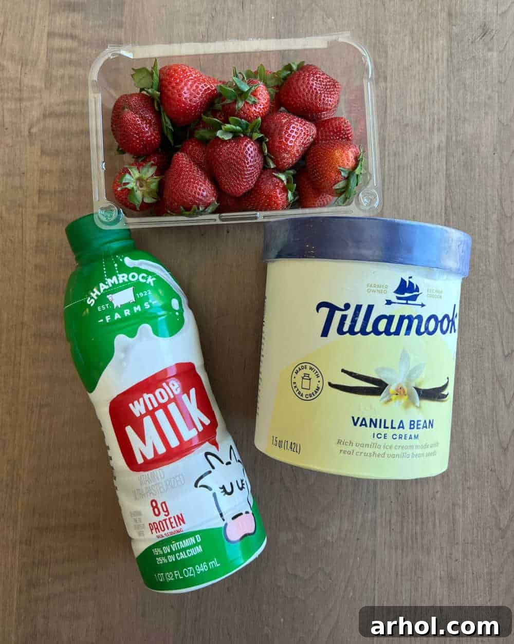 The three essential ingredients for a strawberry milkshake: whole milk, rich vanilla ice cream, and perfectly ripe fresh strawberries, ready for blending.