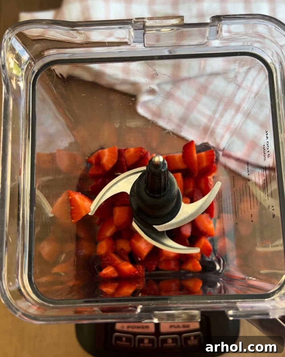 Sliced fresh strawberries are placed at the bottom of a blender, ready for the other ingredients.