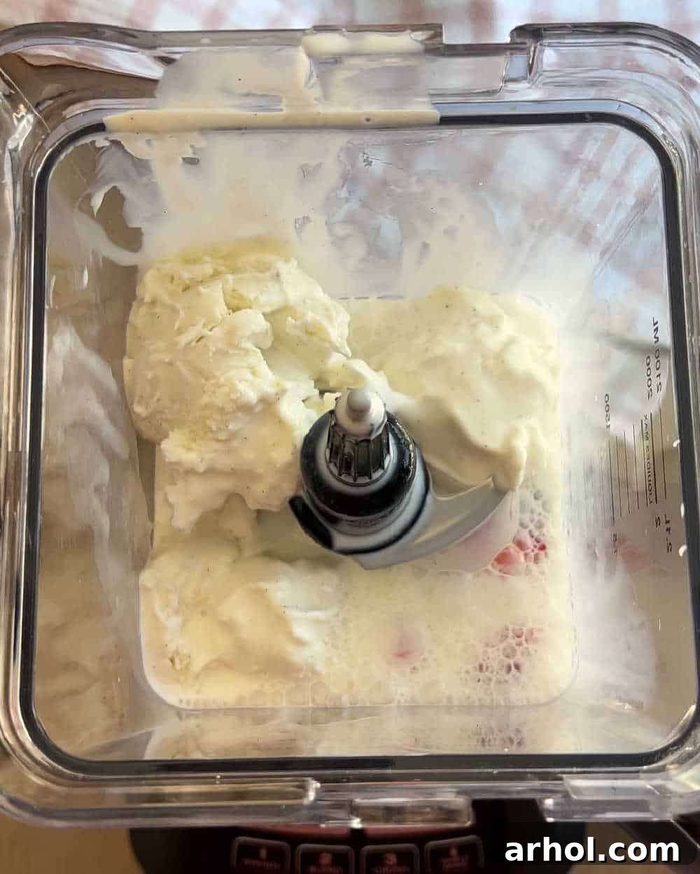 All three ingredients – strawberries, vanilla ice cream, and milk – are layered in the blender, ready to be transformed into a delicious milkshake.