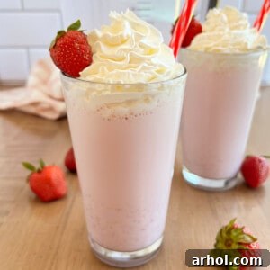 Homemade strawberry milkshake with whipped cream and fresh strawberry in glass.