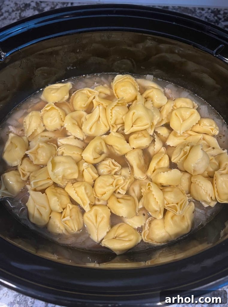 Fresh tortellini and spinach added to the chicken soup in the crockpot.