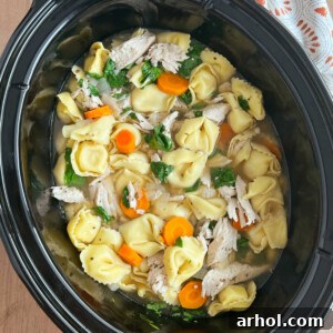Crock Pot Chicken Tortellini Soup with carrots and fresh spinach in the slow cooker.