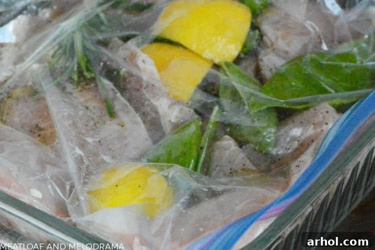 Thin-cut pork loin chops marinating in a zip-top bag with fresh lemon slices and rosemary springs.