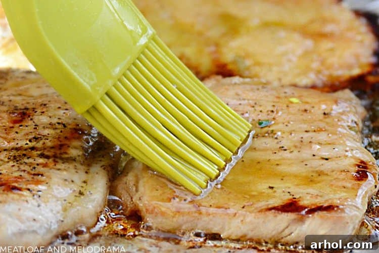 Chef basting pork loin chops on a grill with a lemon balsamic sauce.
