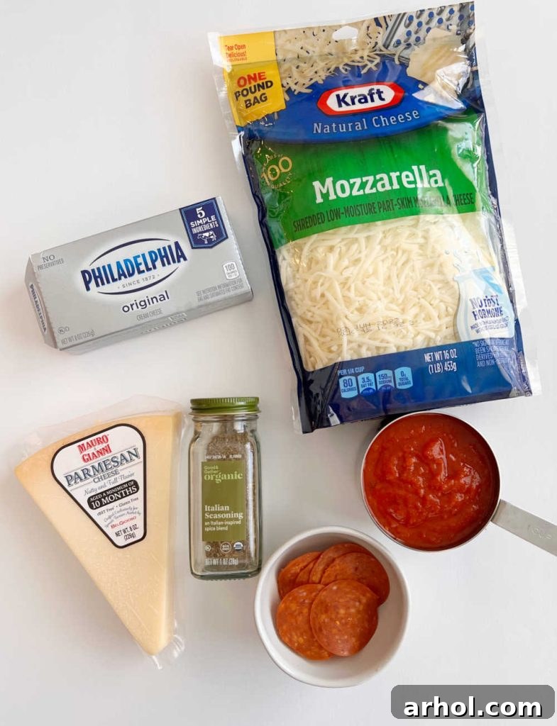 Individual ingredients laid out on a surface: a block of cream cheese, a bowl of shredded Parmesan cheese, Italian seasoning, a bowl of marinara sauce, shredded mozzarella cheese, and slices of pepperoni.