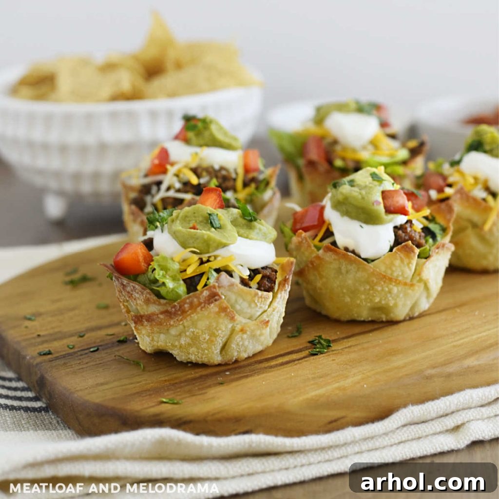 Mini Taco Salad Cups arranged artfully on a rustic wood serving board, showcasing their vibrant ingredients and crispy wonton shells.