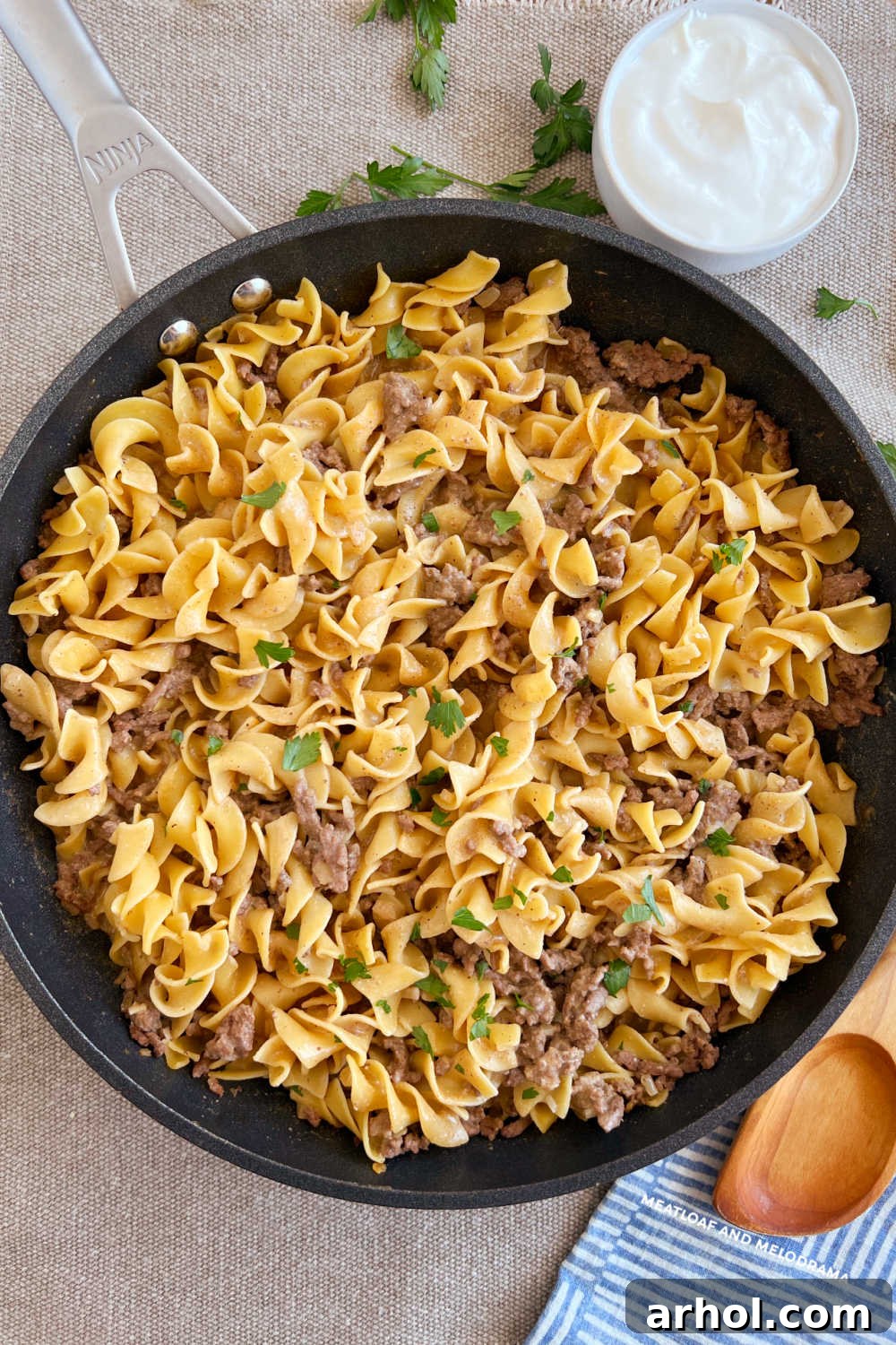 Better-Than-Boxed Ground Beef Stroganoff 7 Finished ground beef stroganoff in skillet with dollop of sour cream and fresh parsley garnish