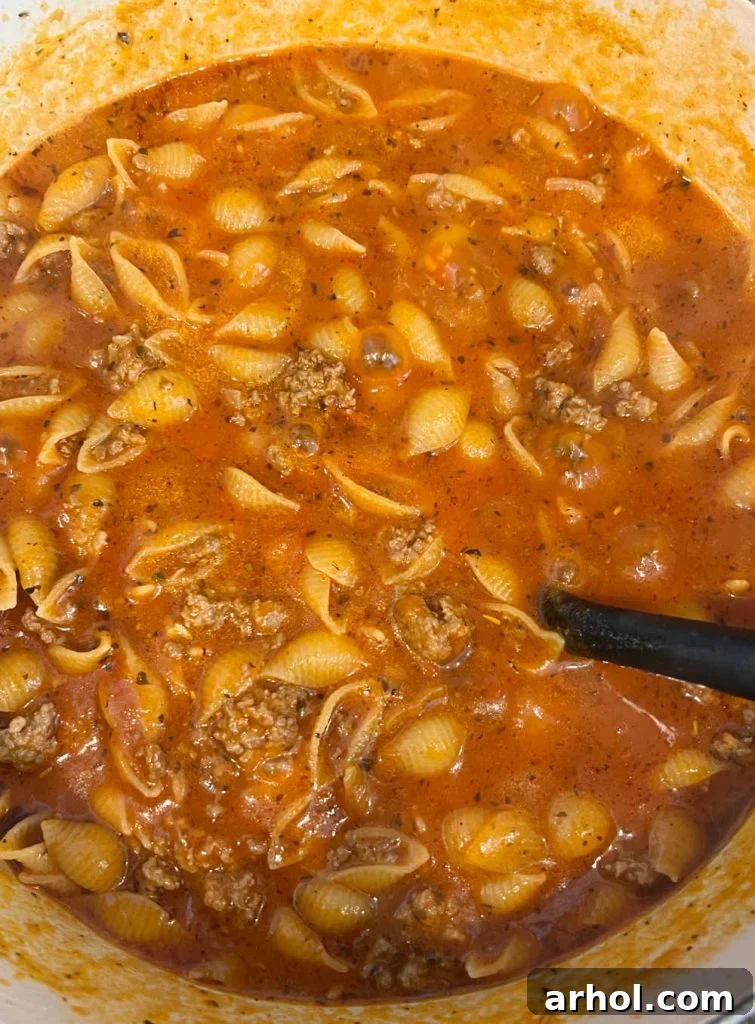 Stir in marinara sauce, water, and uncooked pasta into the Dutch oven with ground beef.