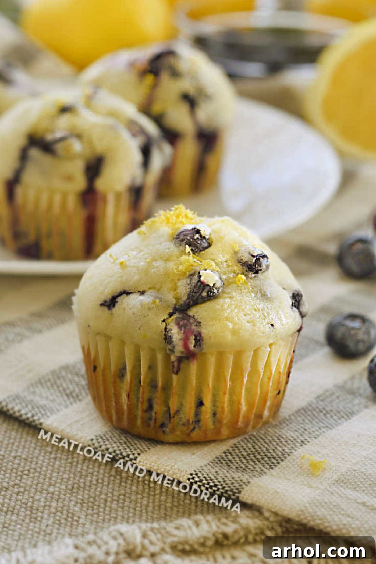 Glazed Lemon Blueberry Muffins topped with fresh blueberries and lemon zest, drizzled with a sweet lemon glaze.