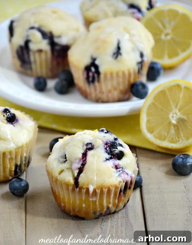 A stack of glazed lemon blueberry muffins on a white plate, ready to be served.
