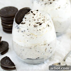 A top-down view of individual no-bake OREO cheesecakes in glass jars, garnished with whipped cream, OREO crumbs, and a whole OREO cookie.