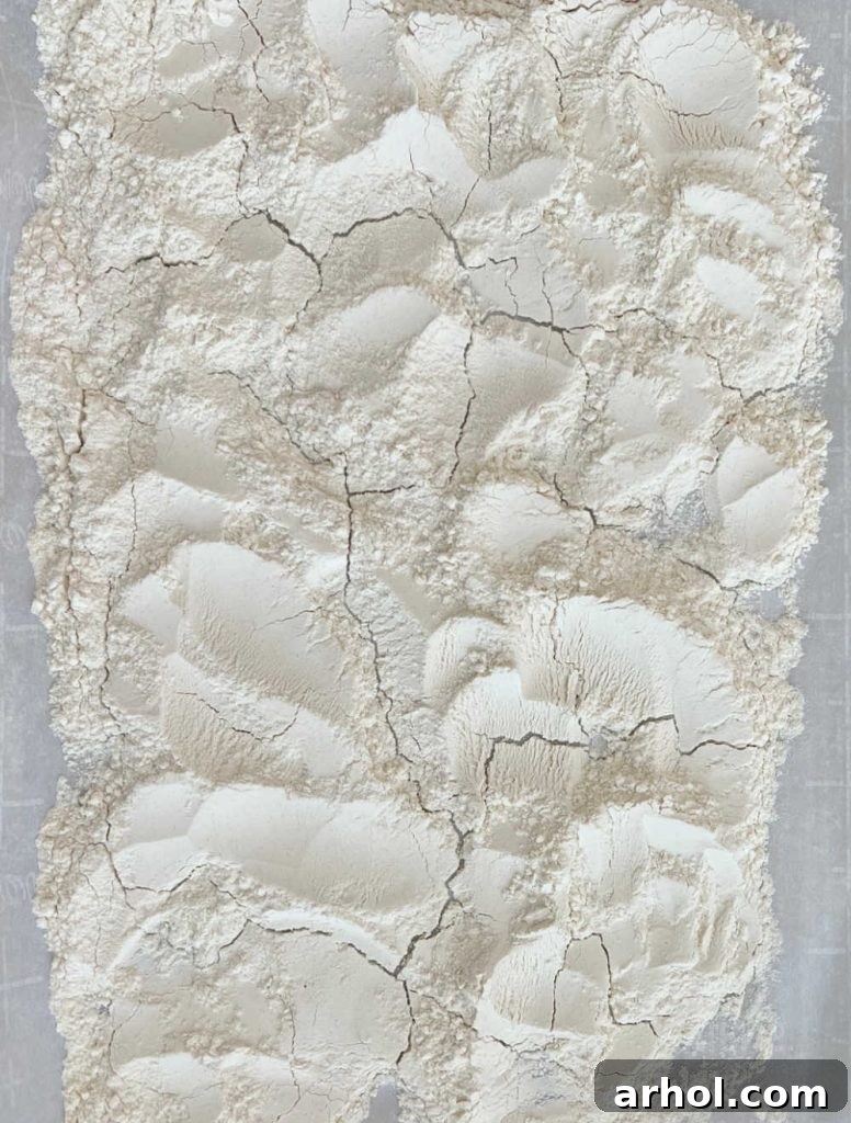 Heat-treated or baked flour spread out evenly on a parchment-lined baking sheet, cooling down.