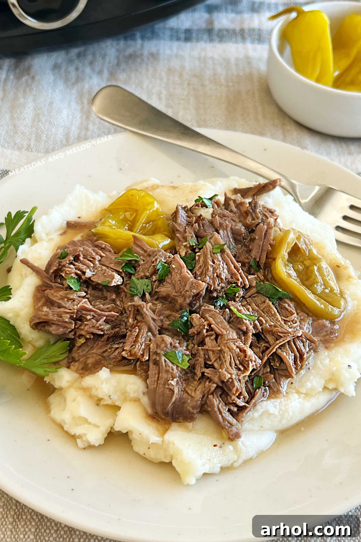 Shredded Mississippi Pot Roast and peperoncini peppers over creamy mashed potatoes