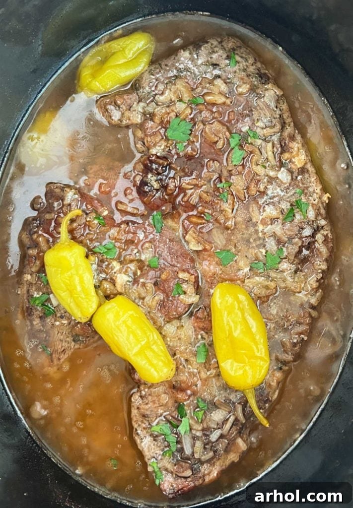 Cooked Mississippi Pot Roast simmering in the slow cooker with tender peppers