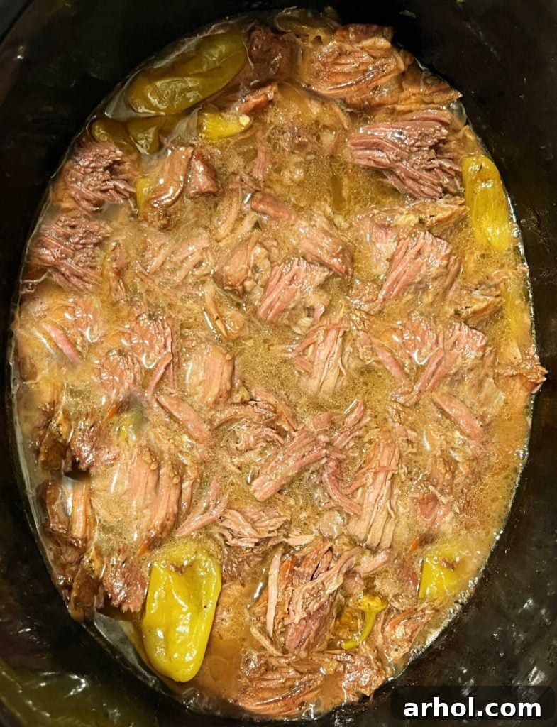 Shredded Mississippi Pot Roast with gravy and peppers in a slow cooker