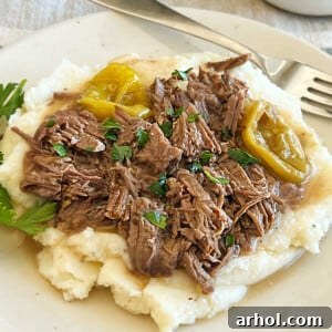 Shredded Crock Pot Mississippi Pot Roast with peperoncini peppers over mashed potatoes