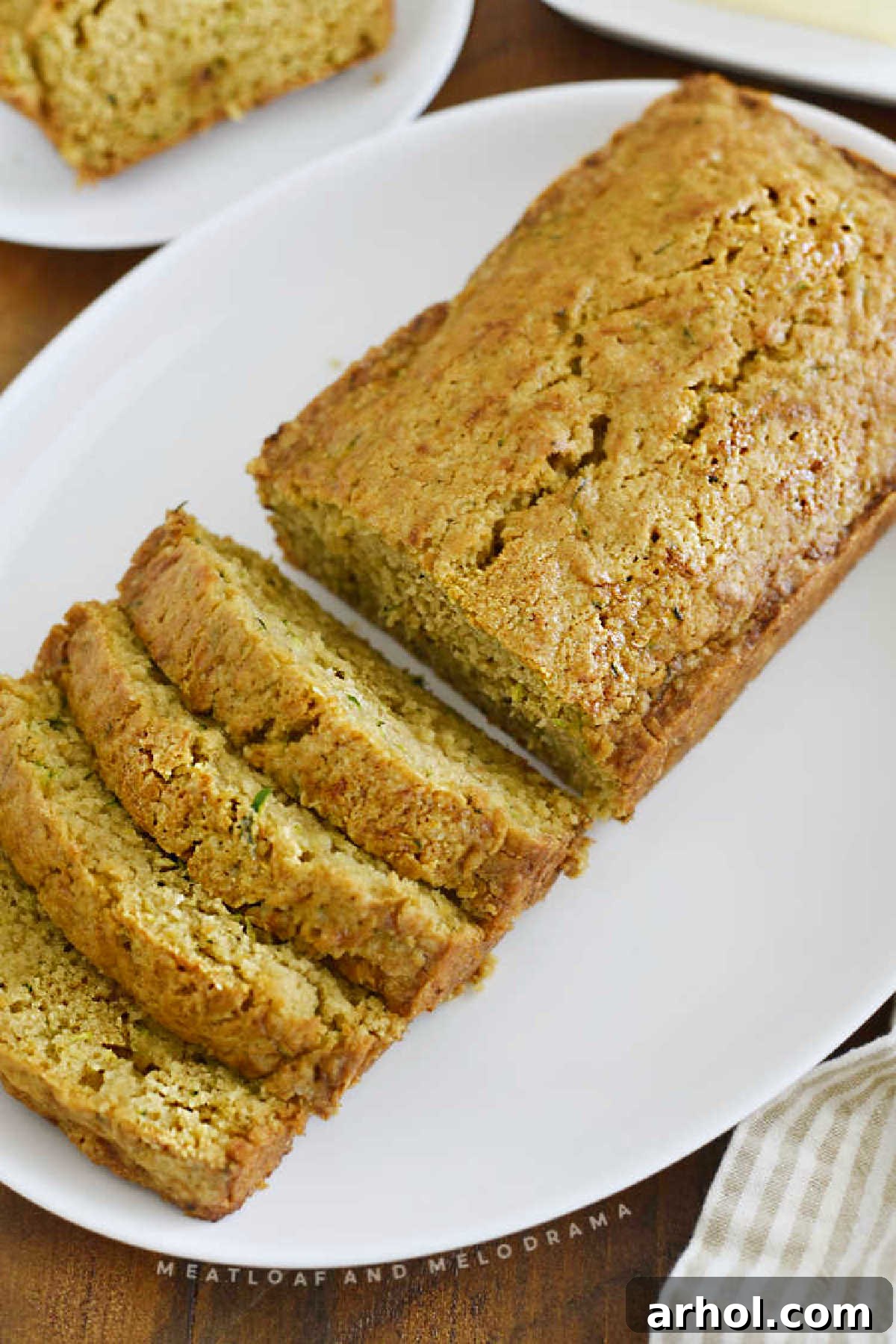 A beautifully baked old-fashioned zucchini bread loaf, freshly sliced and presented on a white platter, invitingly moist.