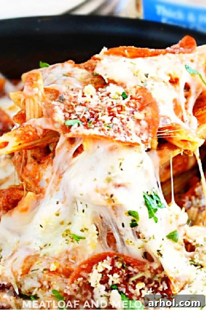 One Pan Pepperoni Pizza Pasta on a serving spoon with irresistible stretchy cheese pull, fresh out of the skillet.