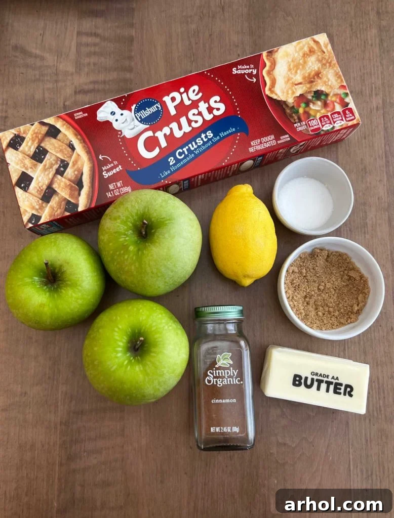 Arrangement of key ingredients: Pillsbury pie crusts, fresh Granny Smith apples, a lemon, butter sticks, brown sugar, white granulated sugar, and ground cinnamon.