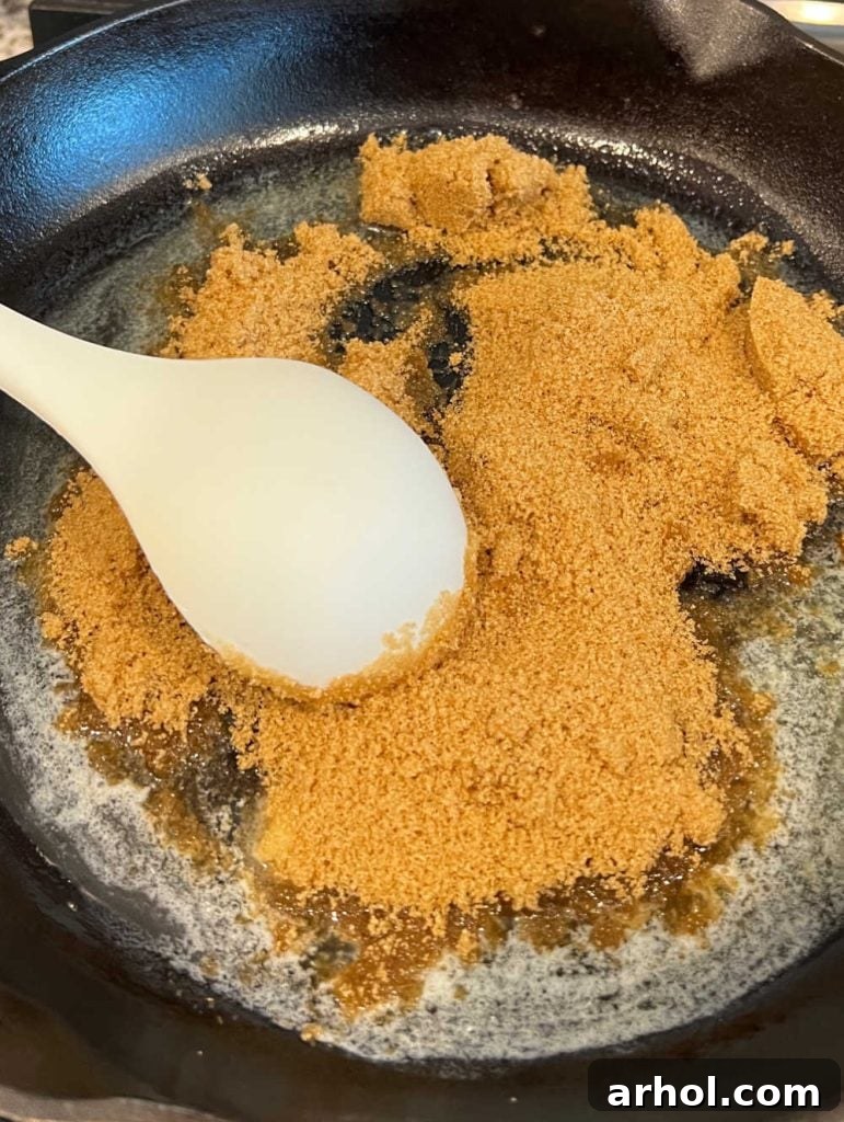 Melted butter and brown sugar simmering together in a cast iron skillet, forming the pie's caramel base.
