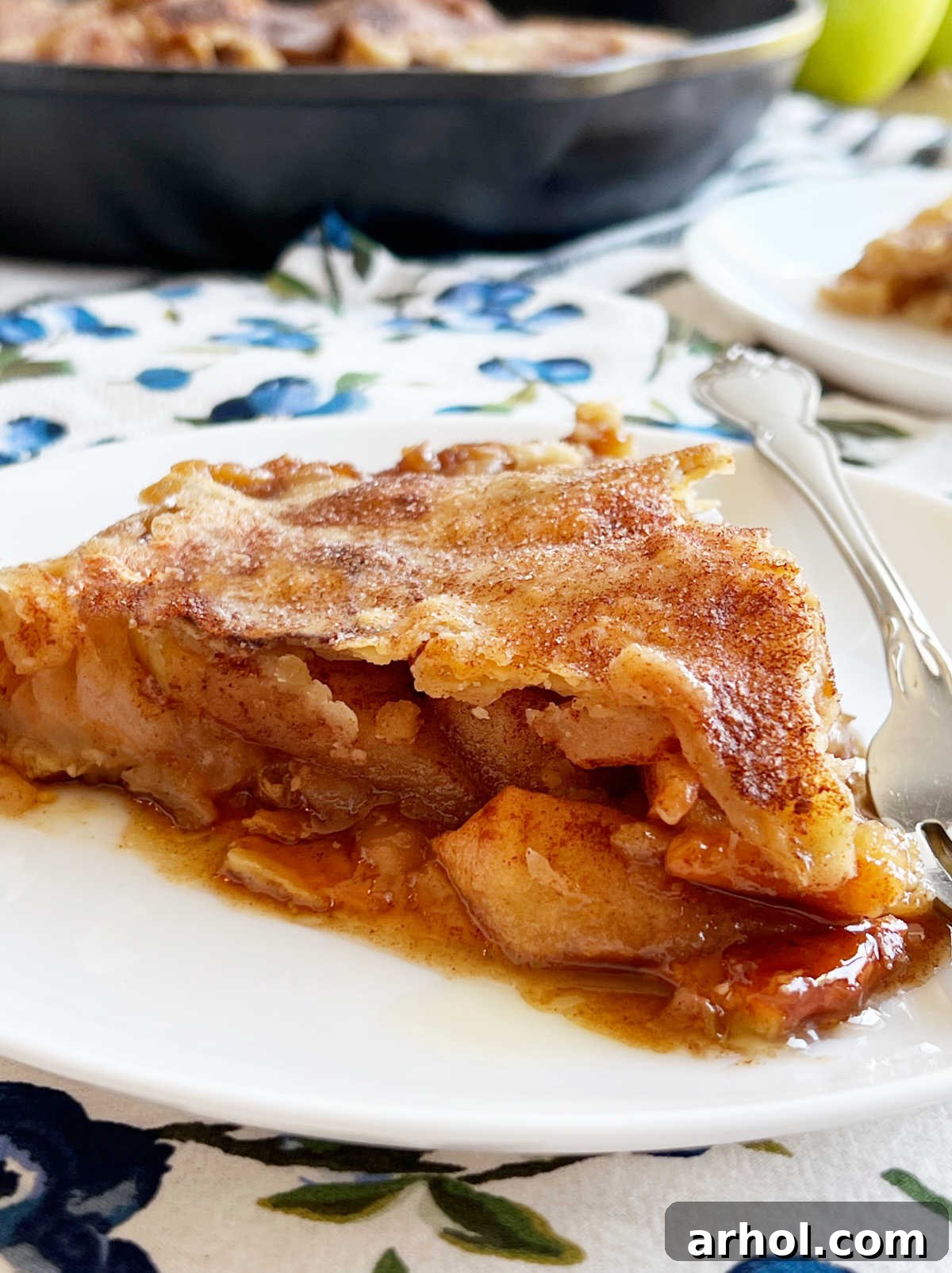 A close-up of a slice of apple pie swimming in rich caramel sauce on a plate, ready to be devoured.