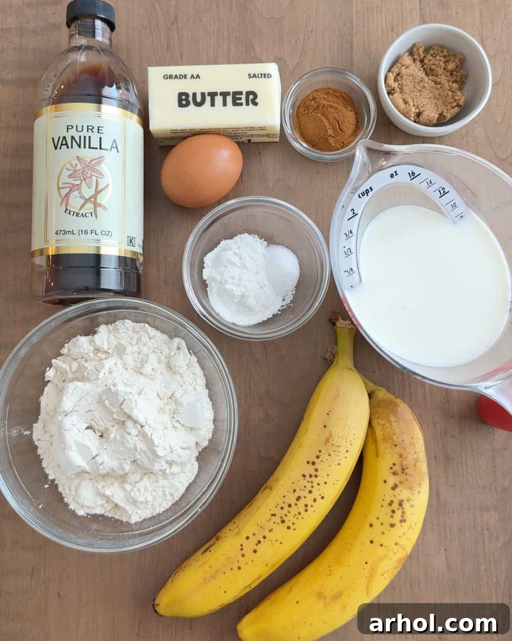 Close-up of ingredients for banana cinnamon pancakes, including ripe bananas, cinnamon sticks, flour, egg, and milk, on a rustic surface.