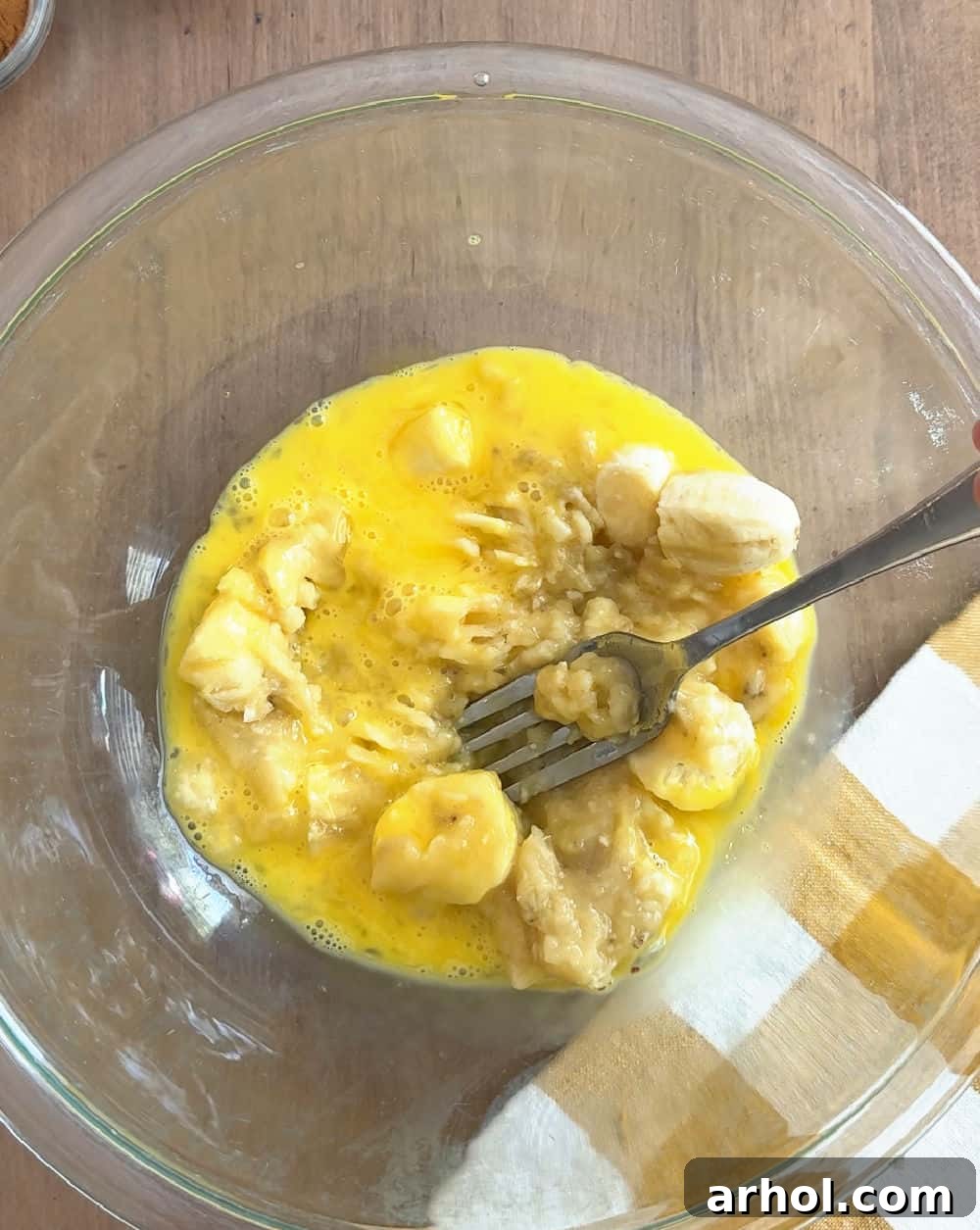 Mashing ripe bananas with a beaten egg in a glass bowl, a crucial first step for fluffy banana pancakes.