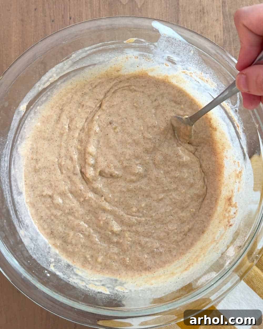 Mixing the fluffy banana pancake batter in a bowl with a wooden spoon, showcasing the perfect, slightly lumpy consistency.