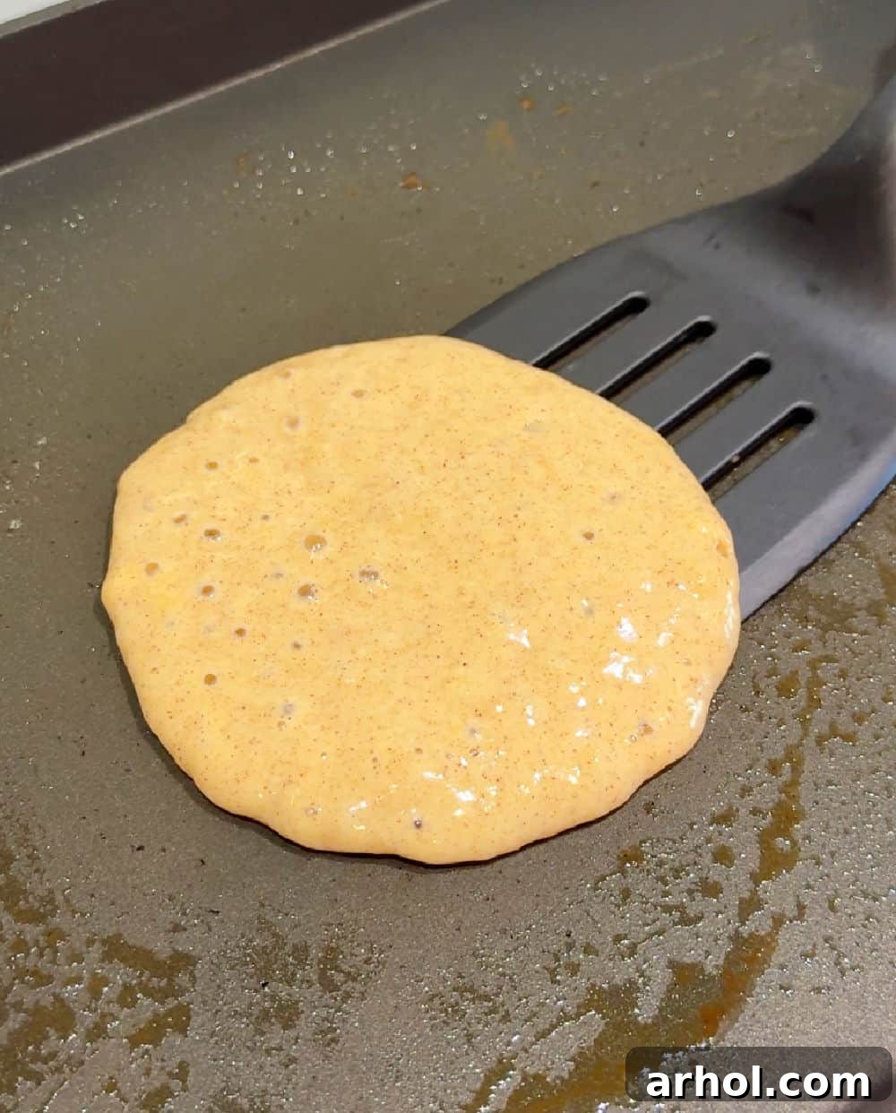 Flipping a golden-brown banana pancake on a griddle, showing the ideal crispy edge and fluffy texture.
