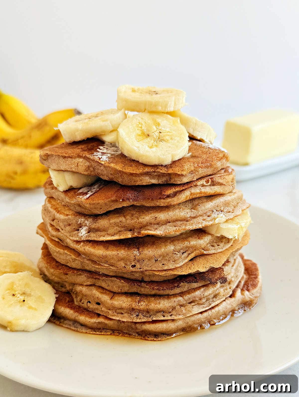 A stack of fluffy banana pancakes on a plate, garnished with fresh banana slices, ready for a delicious breakfast.