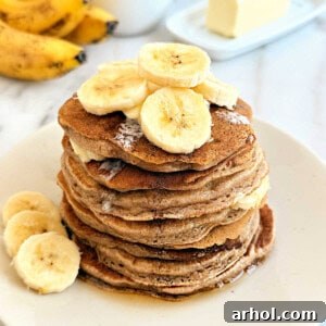 Stack of fluffy banana cinnamon pancakes on a plate, garnished with a sprinkle of cinnamon, ready for breakfast.