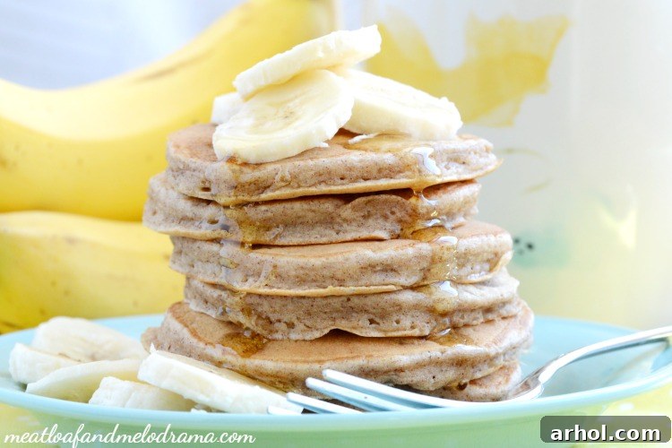 A beautifully arranged breakfast table with a stack of banana cinnamon pancakes, fresh fruit, and coffee, emphasizing a cozy morning feel.