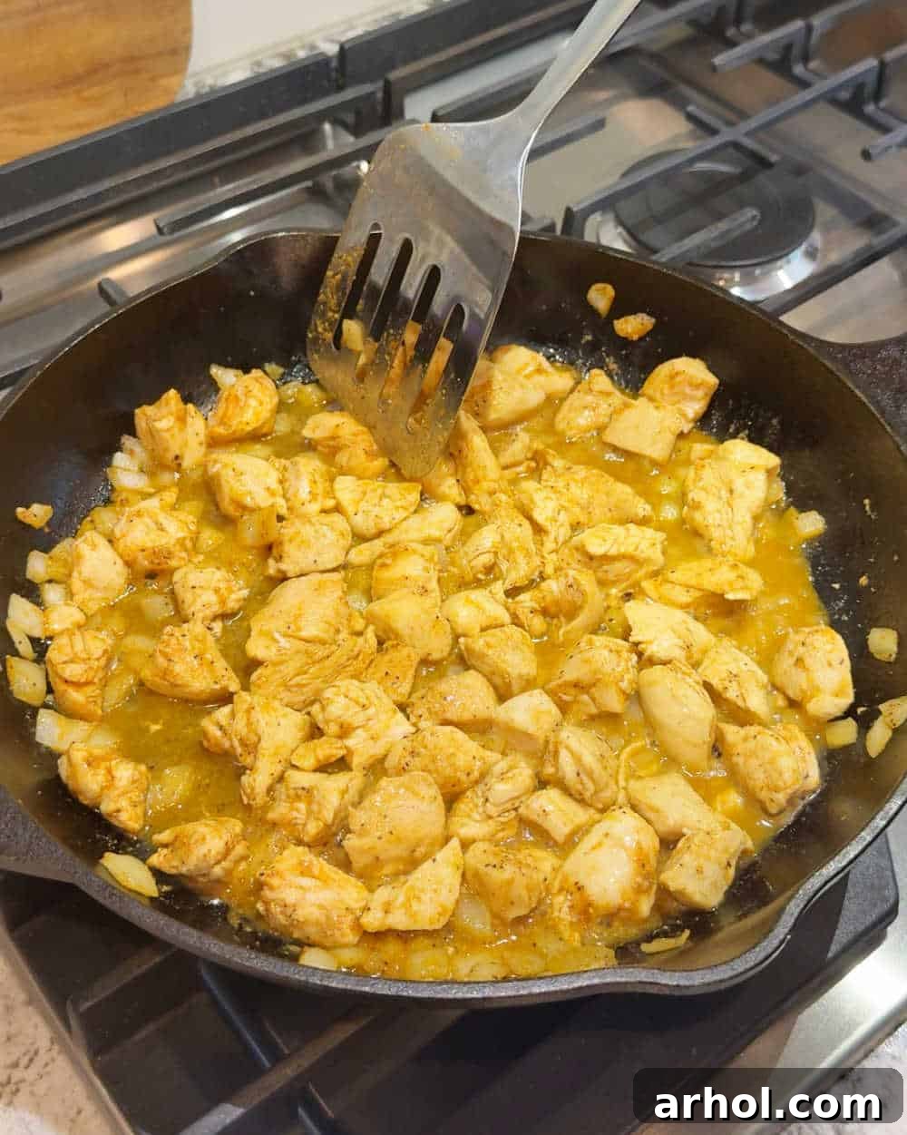 Browning bite-sized chicken pieces with chopped onion in a large skillet, creating a flavorful base for the pasta.