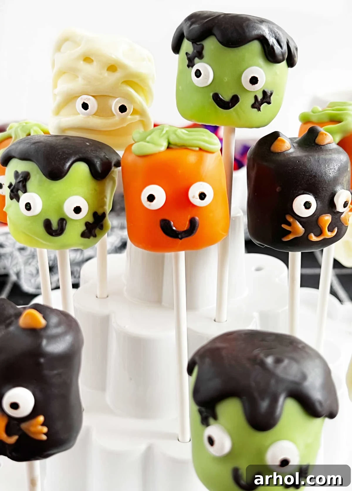 Mummy, black cat, pumpkin and Frankenstein Halloween marshmallow pops on lollipop sticks.