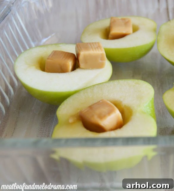 Cut apples with the core scooped out and caramel candies placed in the middle, ready for baking.