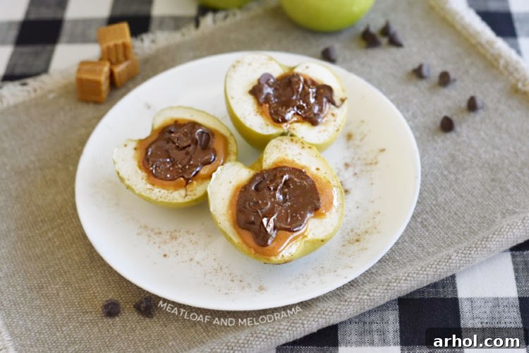 Two halves of baked caramel stuffed apples, topped with vanilla ice cream and an extra caramel drizzle, ready to be enjoyed.