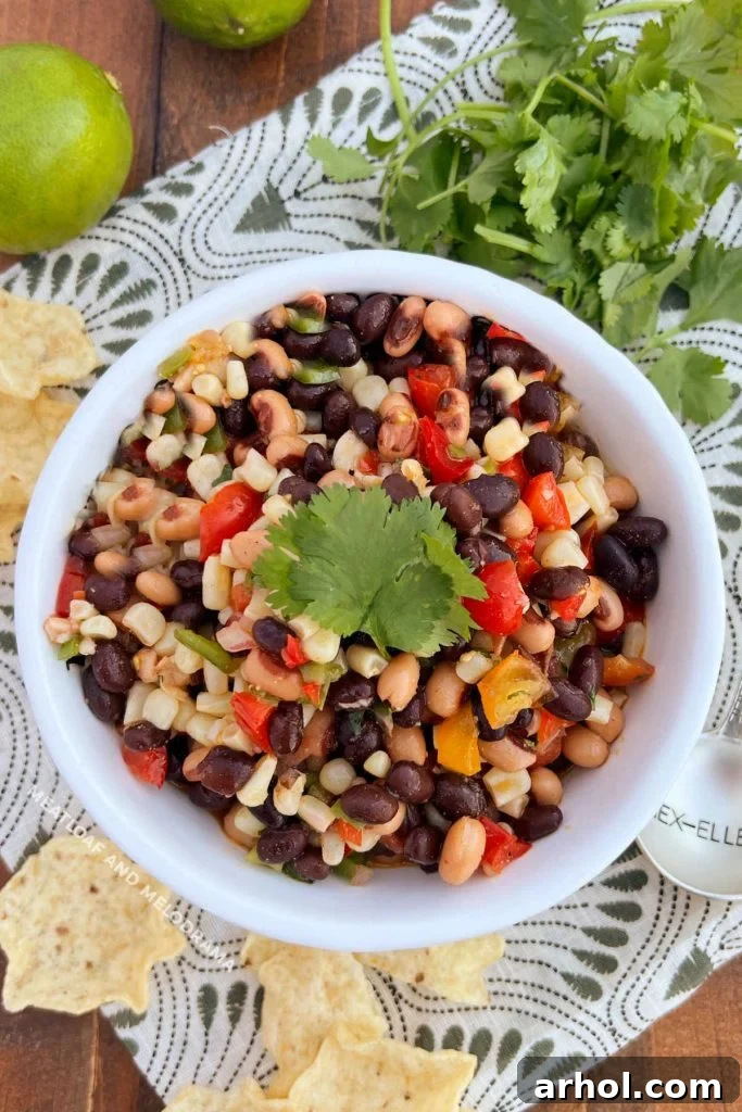 Vibrant Cowboy Caviar (Black Eyed Pea Salsa) served in a white bowl with a side of crispy tortilla chips, perfect for a healthy and delicious appetizer.