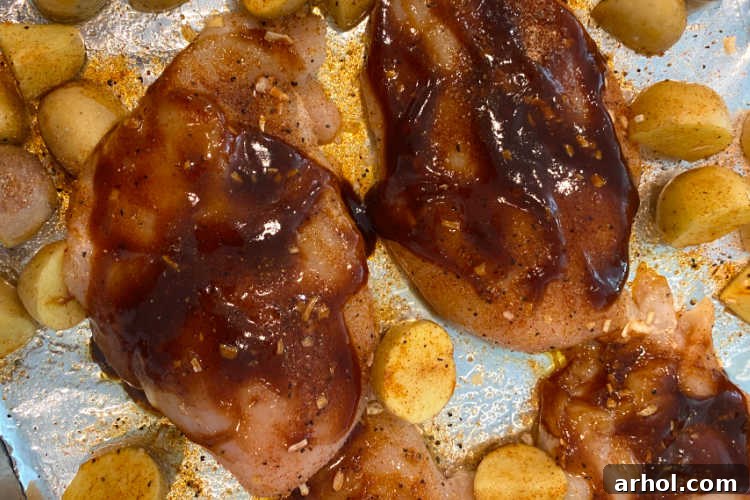 chicken breasts coated with bbq sauce on a baking sheet