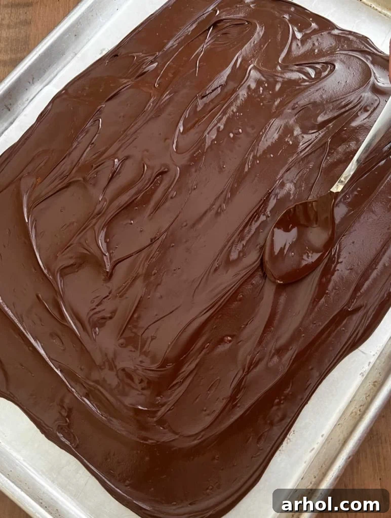 Melted chocolate spread thinly on wax paper on a sheet pan, ready for the next layer of candy melts.
