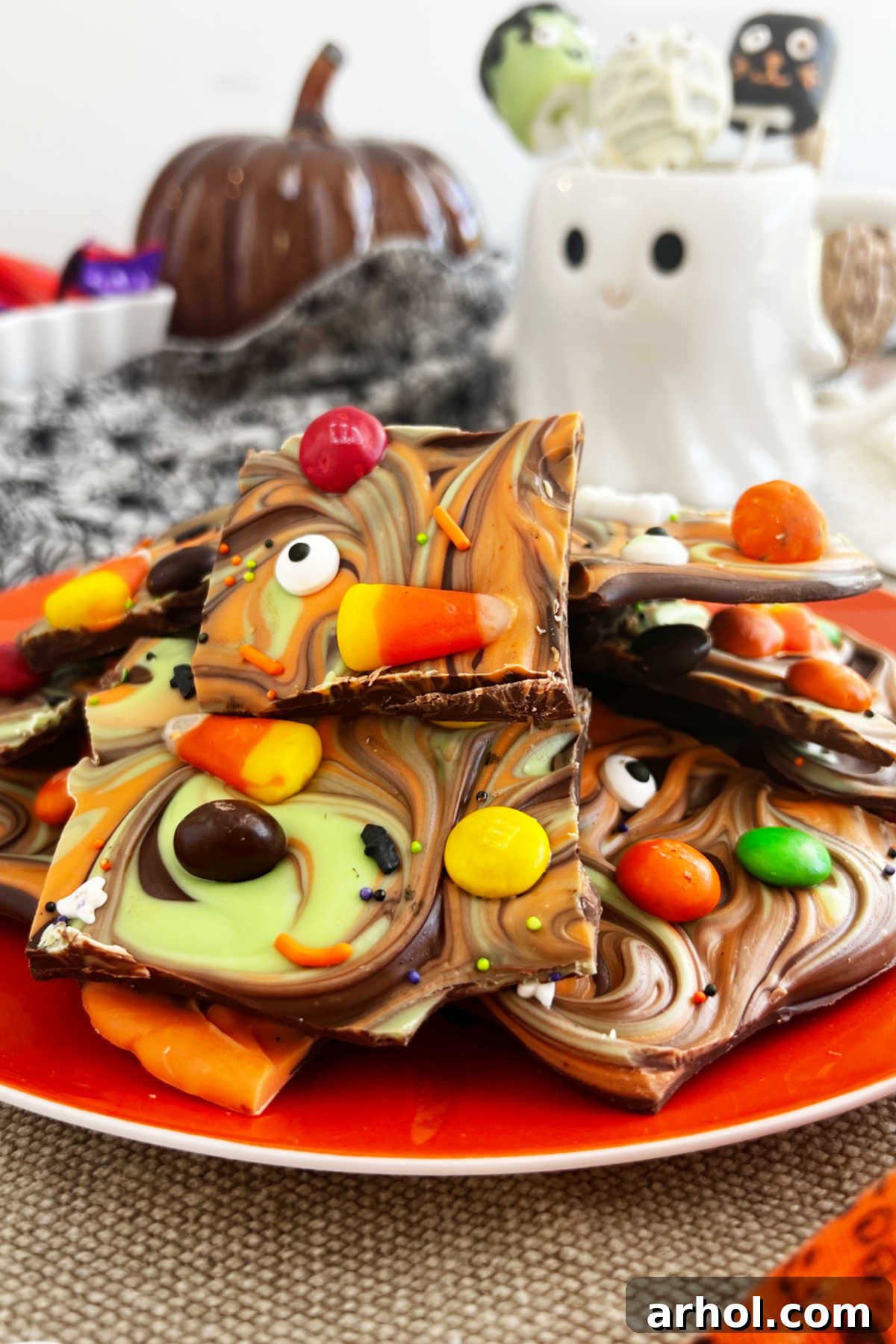 A festive plate piled high with colorful Halloween candy bark, placed on a Halloween party table adorned with spooky decorations.