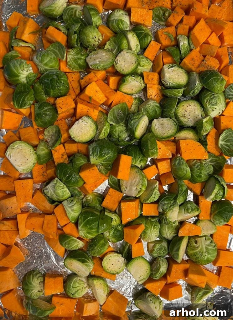 Cut sweet potatoes and Brussel sprouts seasoned on a sheet pan.